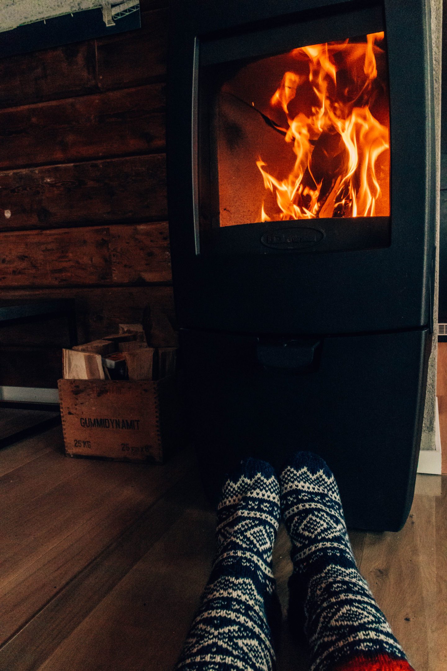 two feet wearing wool marius pattern socks in front of a fireplace