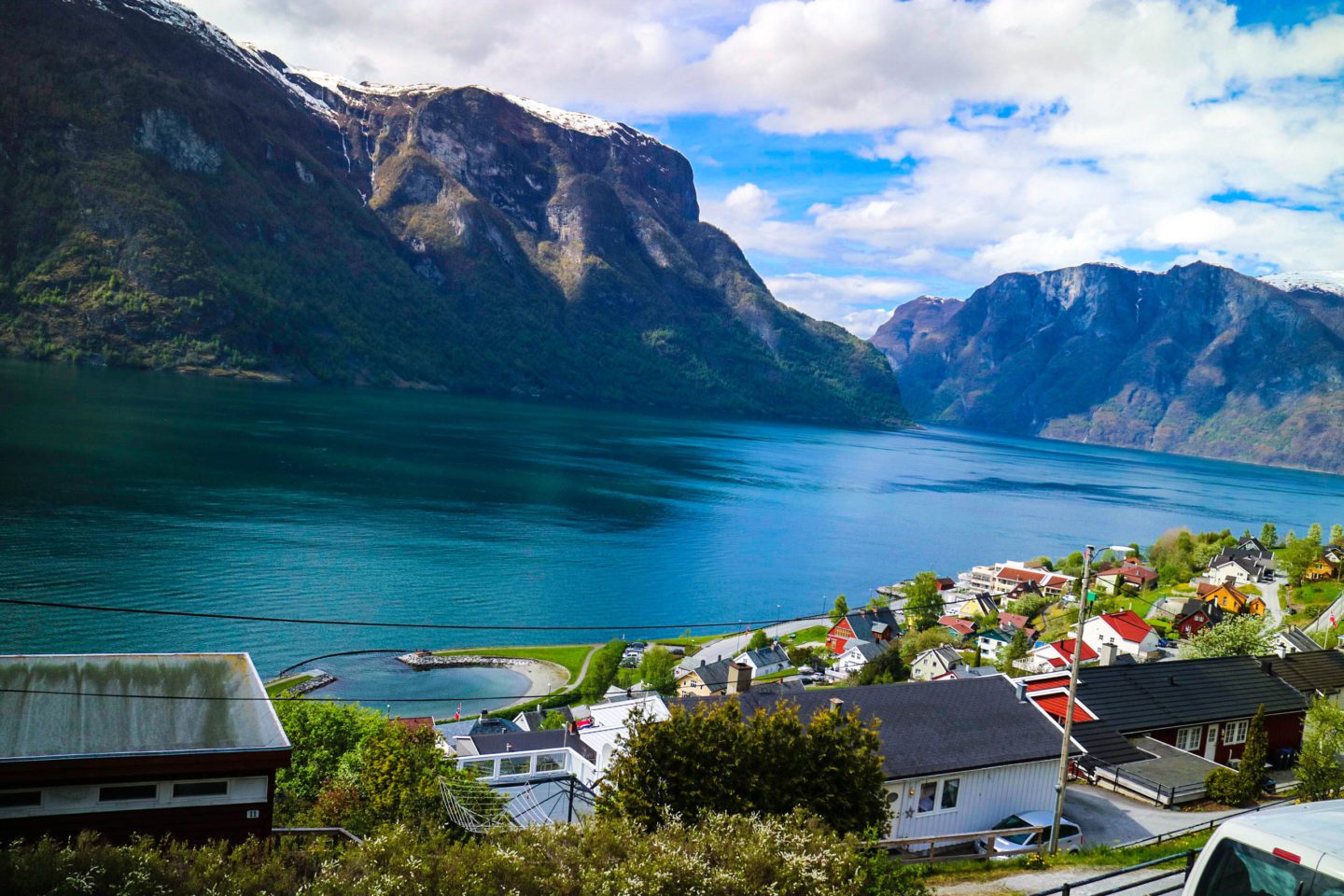 A beautiful fjord landscape, with colourful buildings lining the fjord on one side (a village called Aurland), and steep mountains on the other.