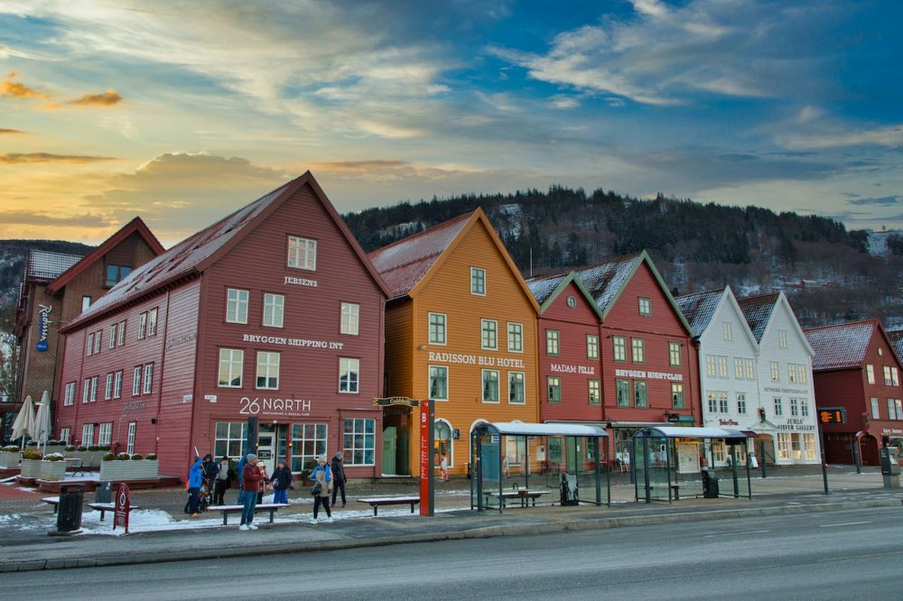 colorful wooden buildings in bergen, norway, with a street and a bus stop in front of them