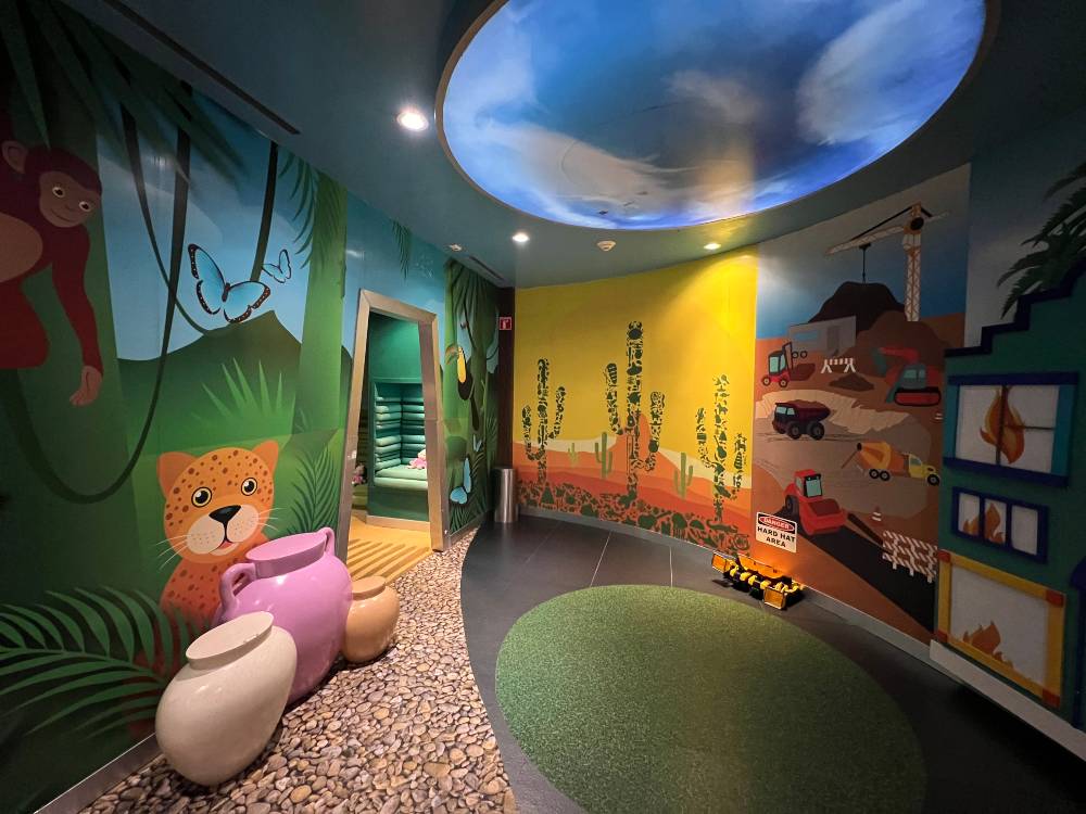 One of the rooms at the Grand Coral Beack Kids club, a room decorated with jungle animals, a desert painting and trucks, tractors and planes.