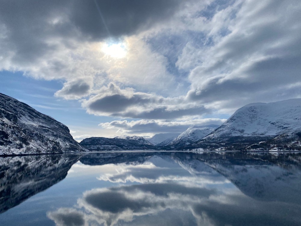 A quiet fjord in Alta, Norway, with skies above reflecting in the water
