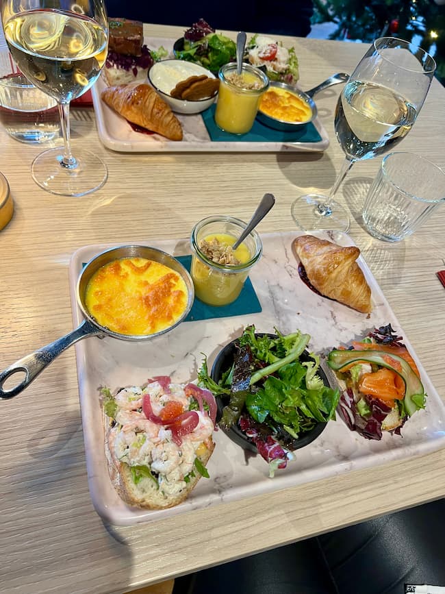 A board of food on a white table, with an omelette, salad and sandwiches on the board.